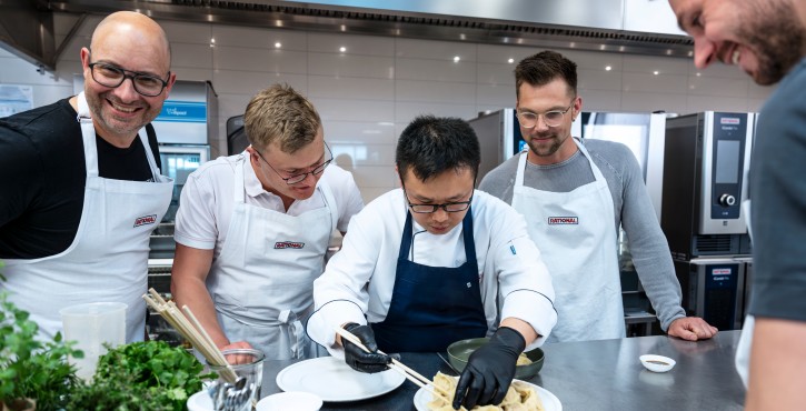 Chef préparant des raviolis avec l’équipe devant des fours mixtes RATIONAL iCombi Pro lors d’une formation culinaire.