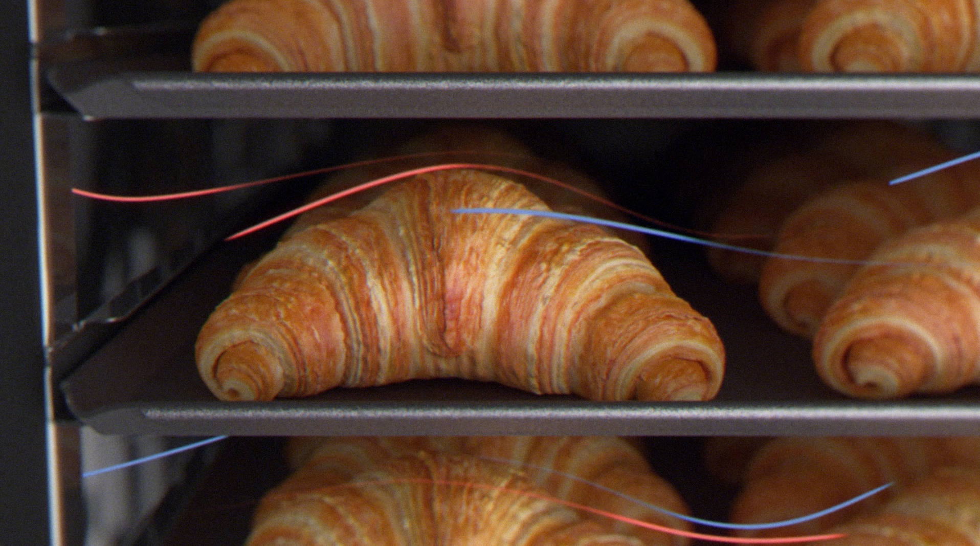 Golden croissants baking evenly in RATIONAL iCombi Pro combi-steamer with visible steam and hot air flow.