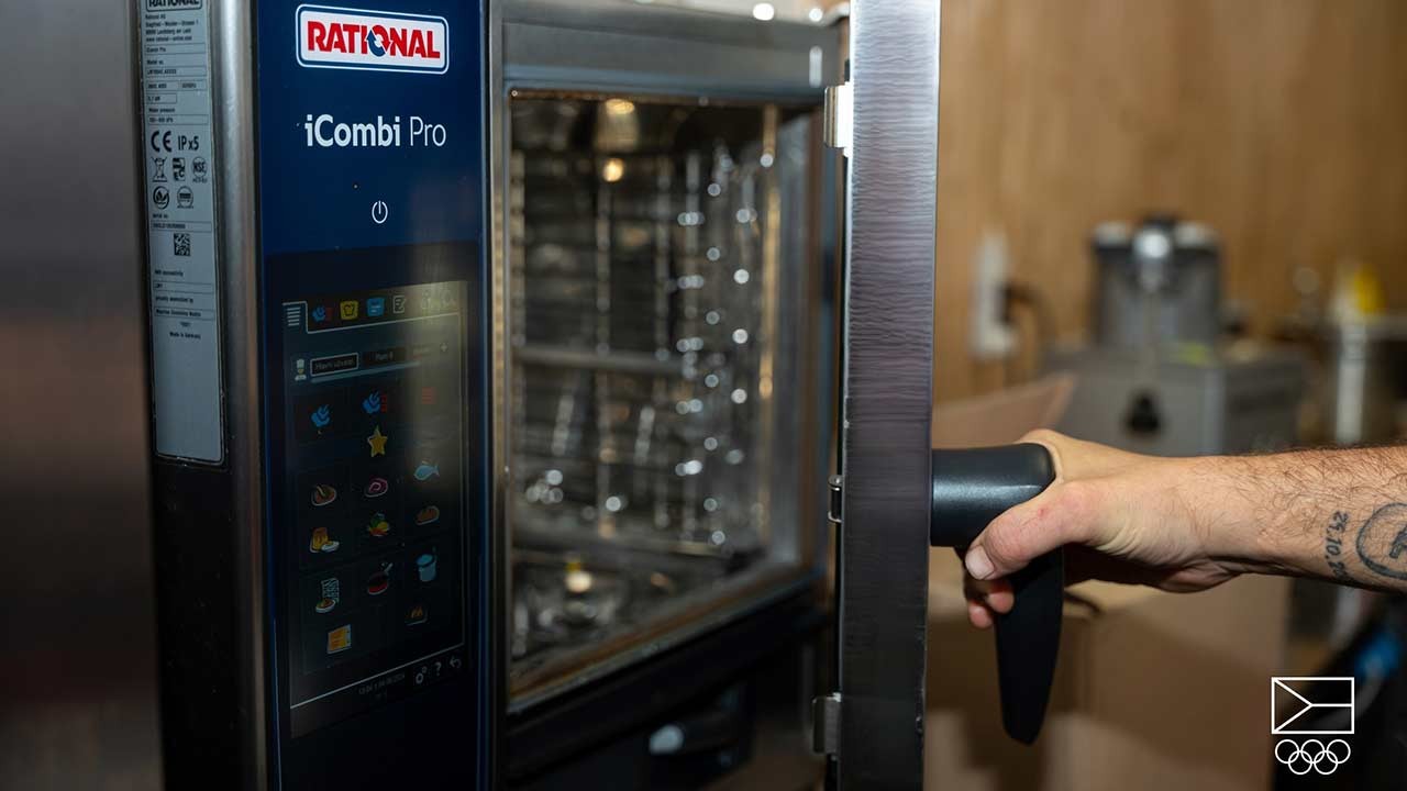 Ruka otevírá RATIONAL iCombi Pro Konvektomat s viditelným dotykovým displejem.