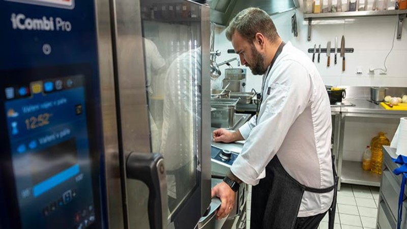 Kuchař pracuje v profesionální kuchyni vedle konvektomatu RATIONAL iCombi Pro.