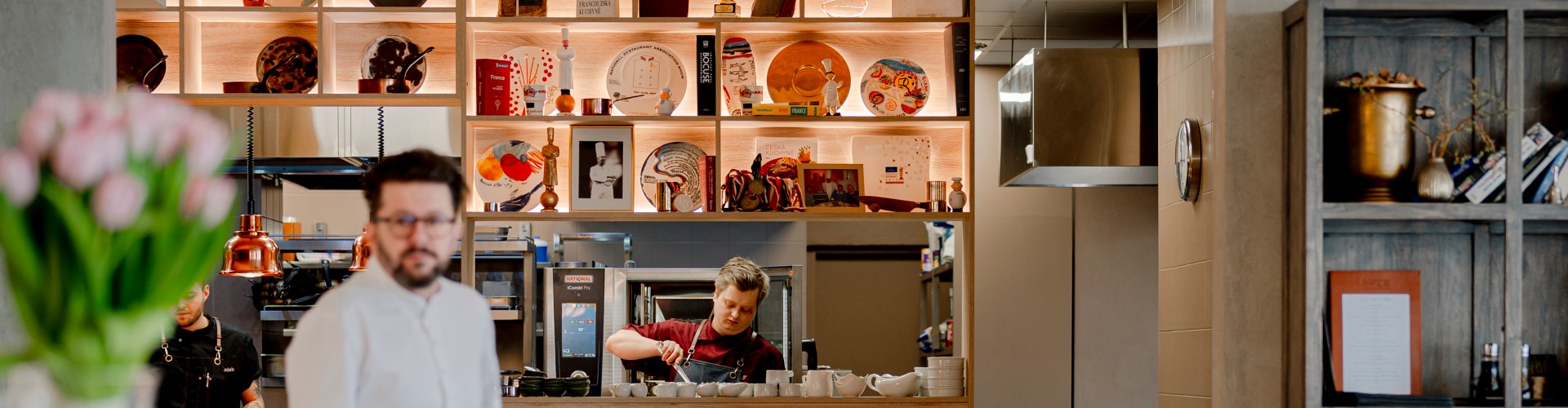 Moderní otevřená kuchyně ve stylové restauraci, kuchaři připravují pokrmy. V pozadí je vidět varný systém Rational iCombi Pro.
