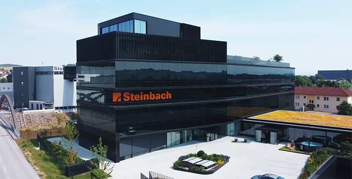 Modernes Firmengebäude von Steinbach Pools mit schwarzer Glasfassade und Dachgarten.