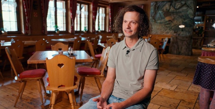 Mann bei einem Interview in einem gemütlichen Restaurant mit Holzmöbeln.