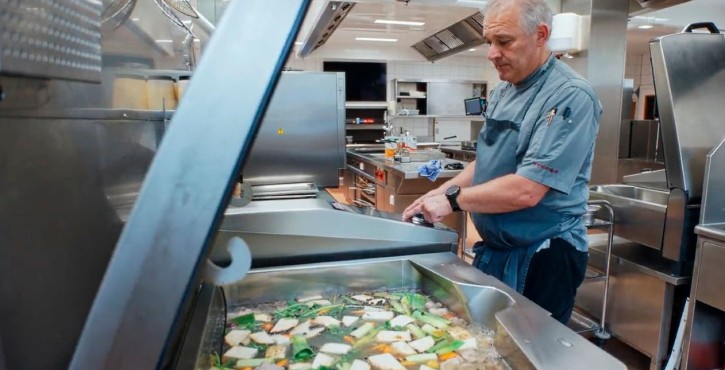 Koch bereitet Fleisch und Gemüse im RATIONAL iVario in einer Profiküche zu.