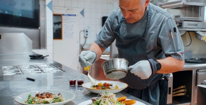 Koch richtet Gerichte sorgfältig in einer professionellen Restaurantküche an.