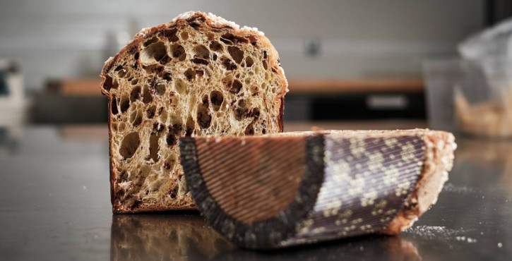 Nahaufnahme eines aufgeschnittenen Panettone mit luftiger, gut aufgegangener Krume auf Edelstahlfläche.