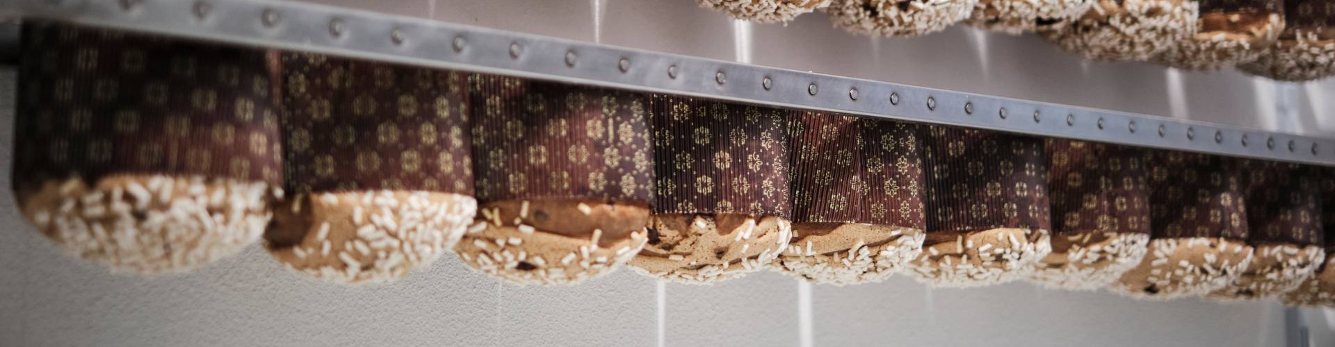 Frisch gebackene Panettoni hängen kopfüber an Gestellen zum Auskühlen und Stabilisieren.