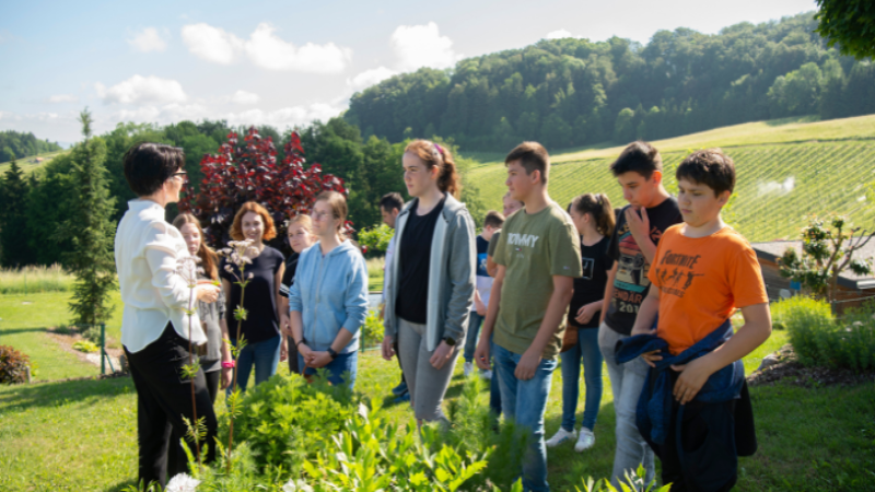 Ausbilderin erklärt einer Gruppe junger Teilnehmender den Kräutergarten mit Landschaftsblick.