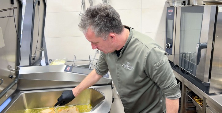 Koch brät Schnitzel im RATIONAL iVario Pro Kochsystem in einer Profiküche.