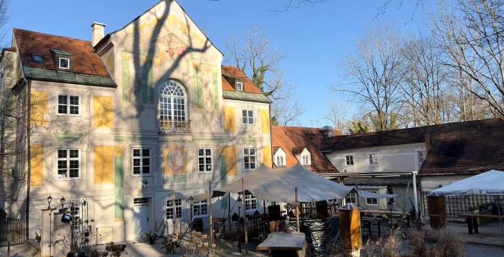 Historische Villa mit bemalter Fassade und Außenbereich mit weißen Zelten an einem sonnigen Wintertag.
