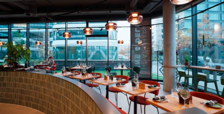Stylish restaurant interior with set tables, large windows and modern lighting.