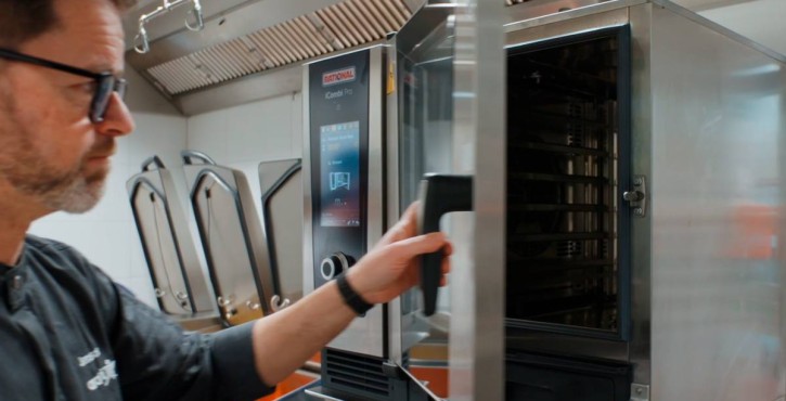 Chef opening RATIONAL iCombi Pro combi oven in a professional kitchen.