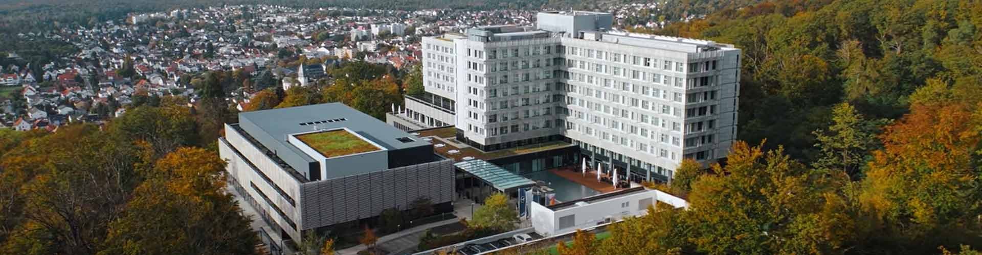 Luftaufnahme des Lufthansa Seeheim Conference Hotels umgeben von Wald und Stadtlandschaft.