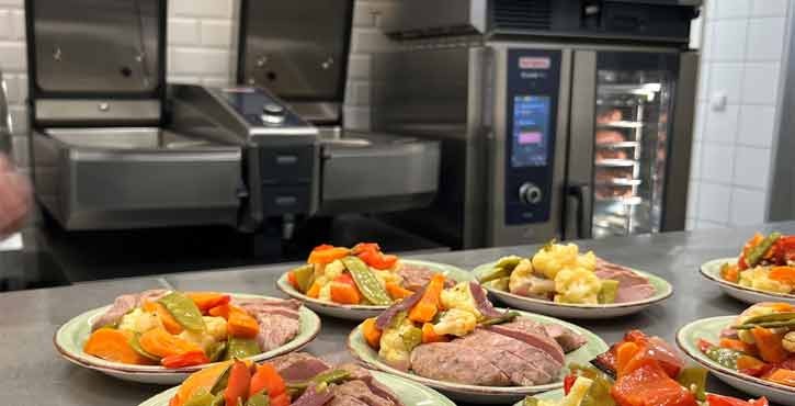 Angerichtetes Fleisch mit Gemüse in Profiküche, RATIONAL iCombi Pro Kombidämpfer im Hintergrund.