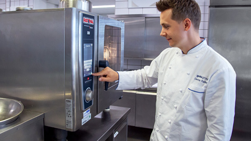Chef operating a RATIONAL SelfCooking Center combi oven in a professional kitchen.
