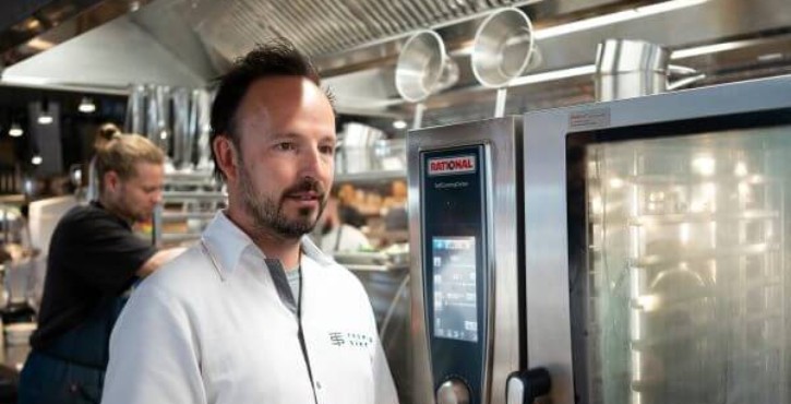 Koch steht an einem RATIONAL SelfCooking Center Kombidämpfer in Profiküche.