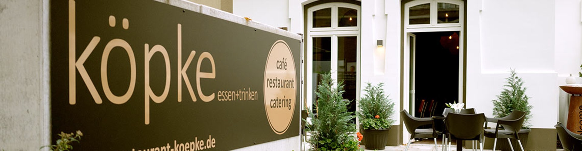 Köpke Restaurantschild neben einem Außenbereich mit Sitzplätzen im Innenhof.
