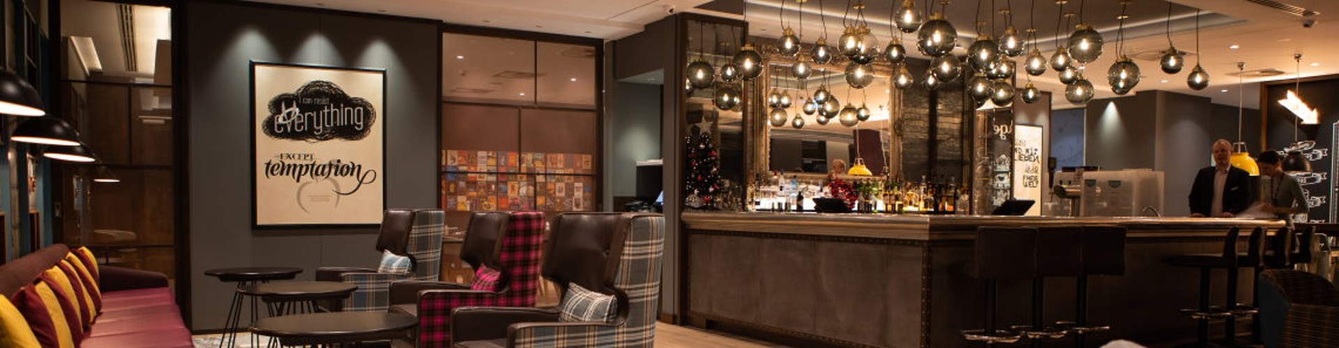 Moderne Hotellounge mit Sitzbereich und beleuchteter Bar.