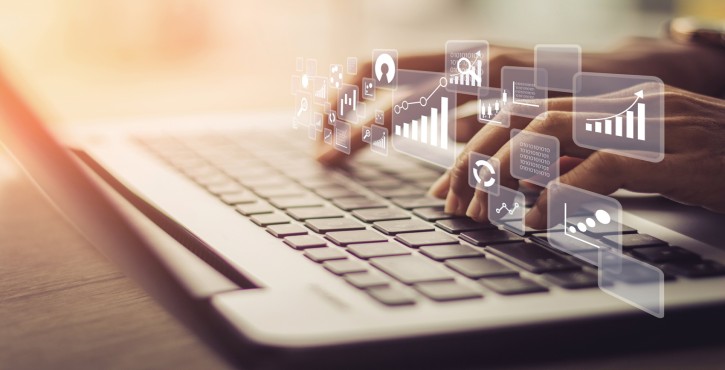 Persona escribiendo en un teclado de laptop con íconos digitales de análisis de datos superpuestos.