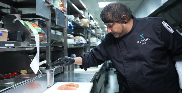 Kitopi chef preparing salmon fillets in a professional kitchen.