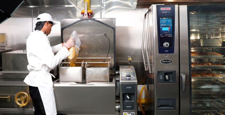 Chef working beside a RATIONAL iCombi Pro combi oven in a commercial kitchen.