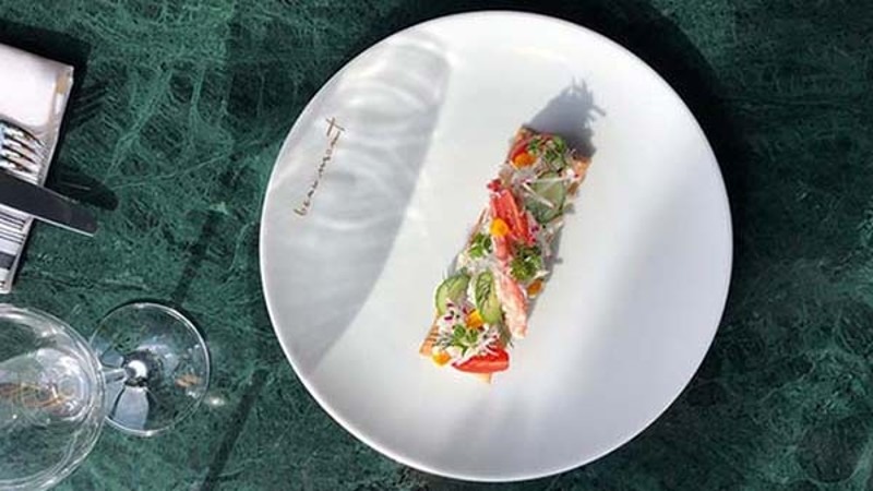 Fine dining plated dish on a white plate over a green marble table.