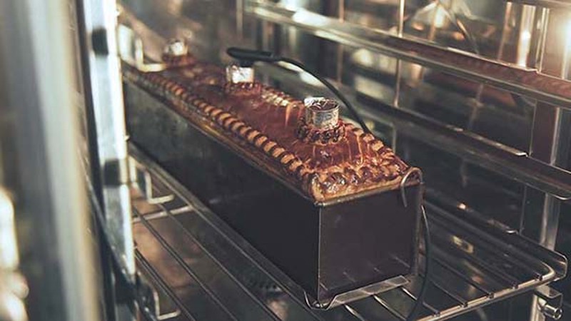 Rectangular loaf pan on an oven rack in a professional kitchen.