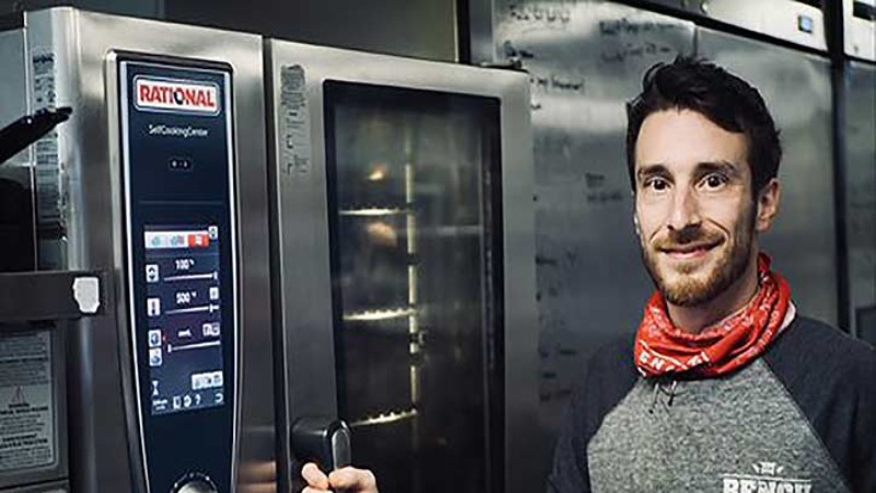 Person standing next to a Rational SelfCookingCenter in a commercial kitchen.