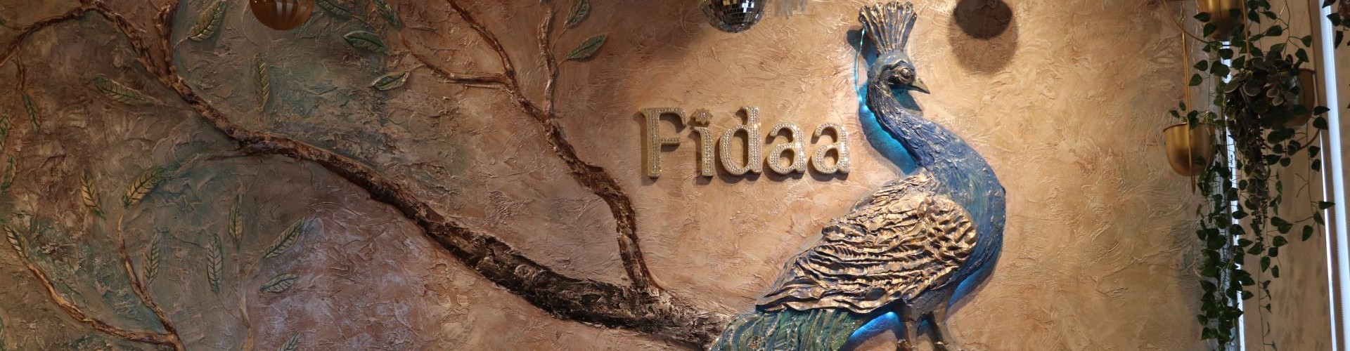 Decorative peacock wall sculpture with Fidaa logo in an elegant restaurant interior.