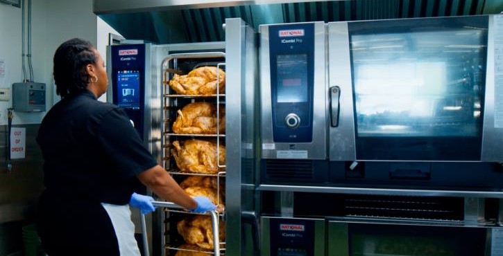 Chef loading rack of seasoned chicken into the RATIONAL iCombi Pro combi oven.