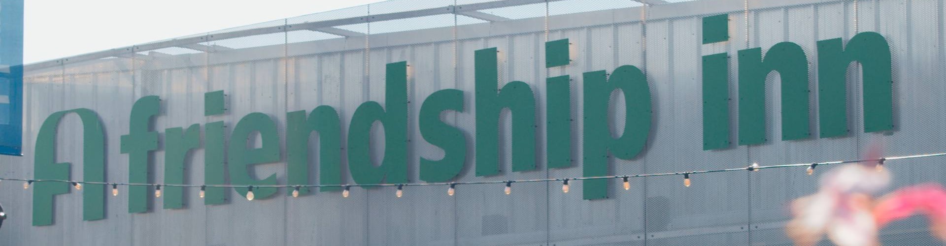 Outside view of the Friendship Inn building with large green signage.