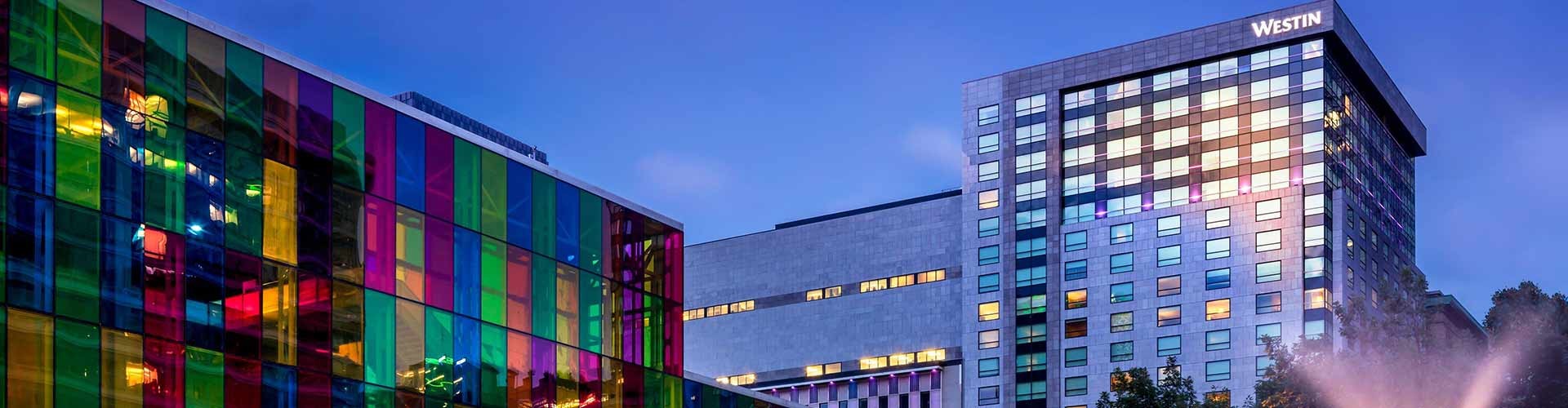 The front view of Le Westin Montreal with colorful glass panels and a fountain.