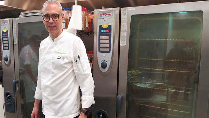 Chef standing next to Rational ovens in a professional kitchen.