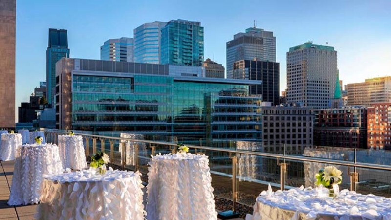 Rooftop terrace with white tables and a city skyline view.