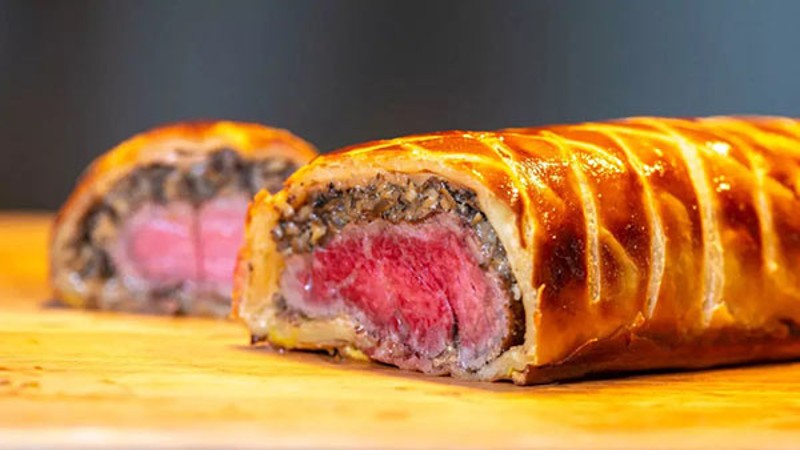 Sliced Beef Wellington with pink center, filled with mushrooms and wrapped in pastry.