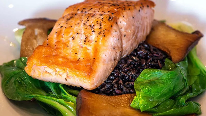 Pan-seared salmon on a bed of spinach, mushrooms, and black rice.