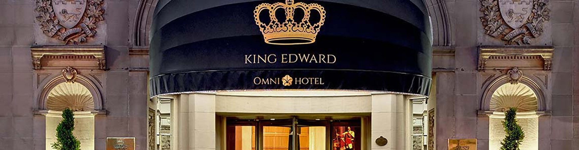 The entrance of the Omni King Edward Hotel with a crown logo above the door.