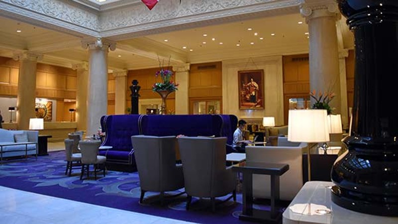 The Omni King Edward Hotel lobby with purple accents, comfortable seating, and columns.