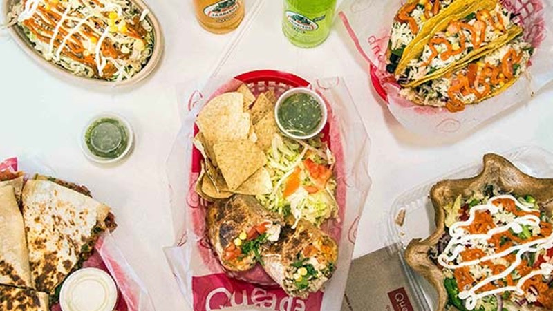 A variety of Mexican food items including tacos, quesadillas, and salsa with drinks.