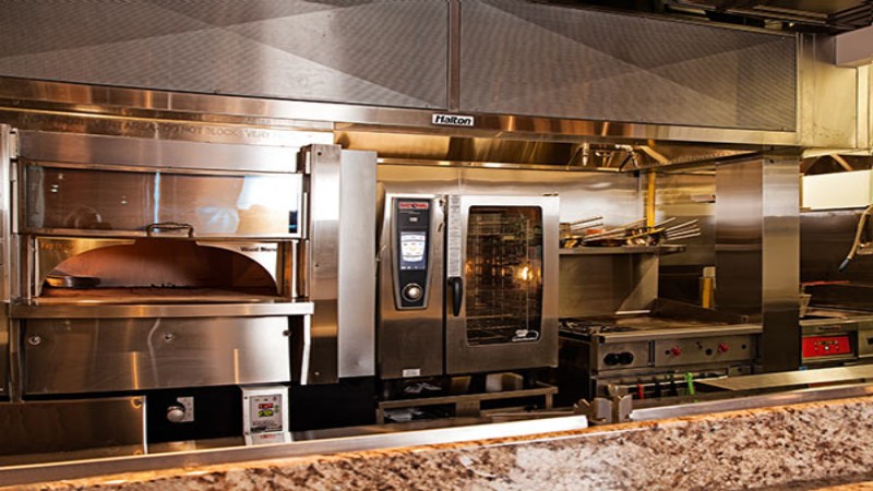 Commercial kitchen featuring a Rational oven and various other stainless steel cooking appliances.
