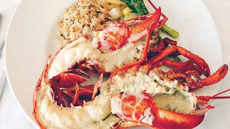 A plate with lobster, rice, and vegetables.