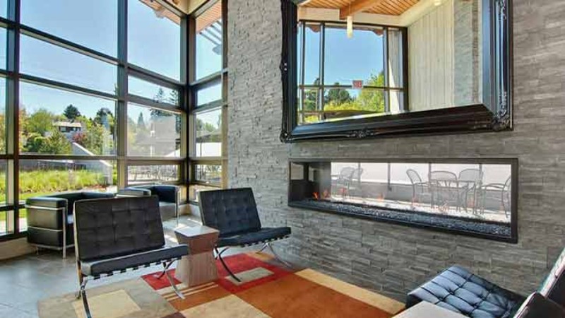 A modern lounge area with comfortable chairs, large windows, and a view of an outdoor terrace.