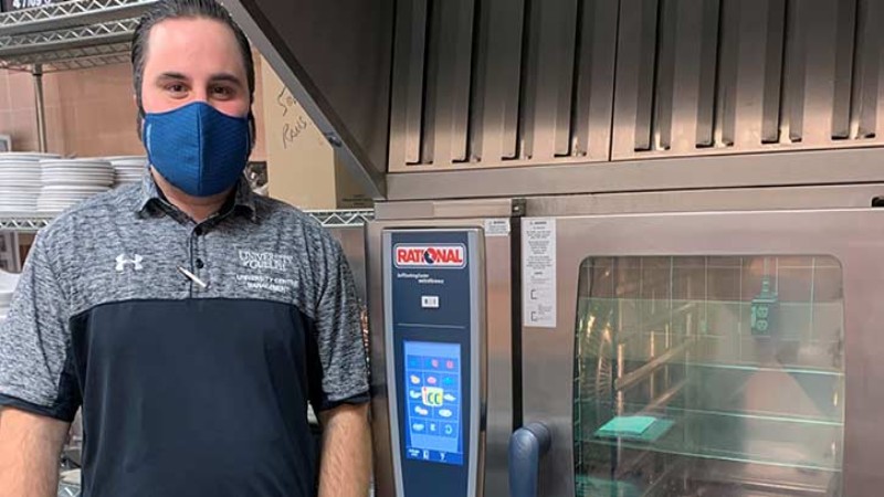 Person stands next to a Rational oven in a commercial kitchen at University of Nevada, Las Vegas.