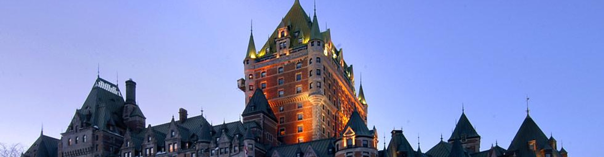 The Château Frontenac in Quebec City, a historic hotel with a distinctive castle-like design, illuminated at dusk.