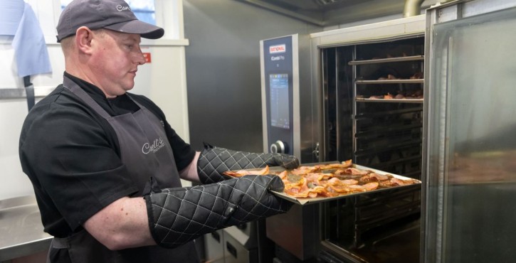 Chef removing tray of bacon from RATIONAL iCombi Pro combi oven.
