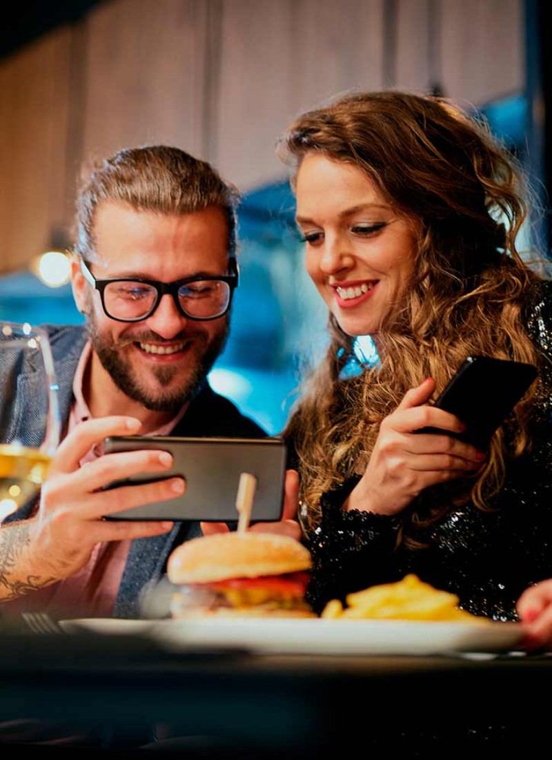 2 adults look at their phones in a restaurant