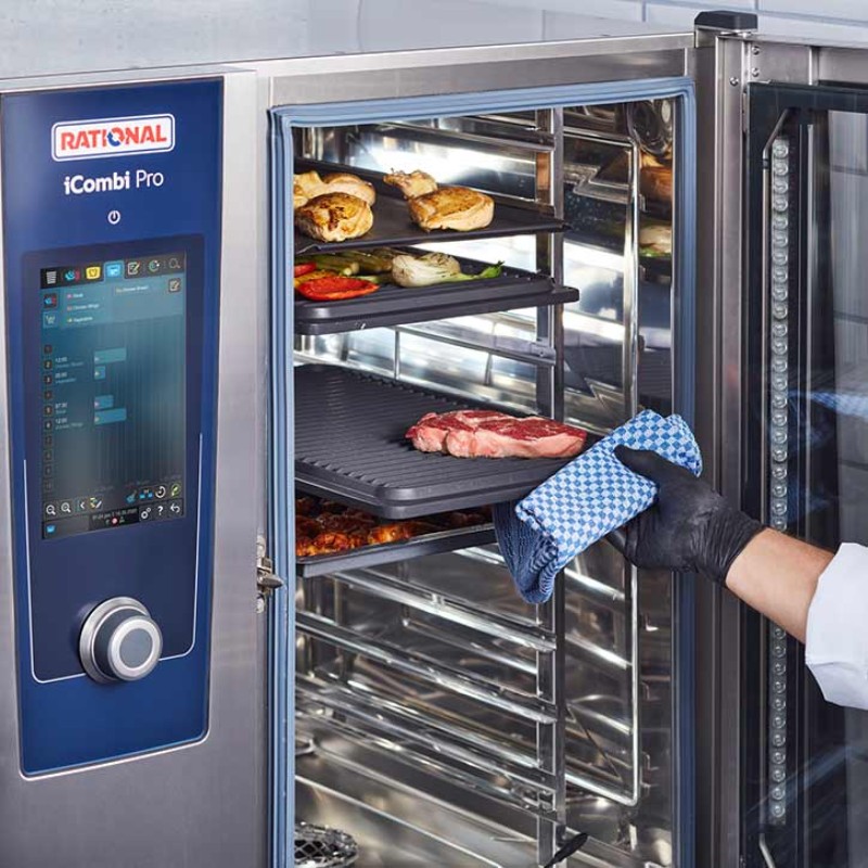 A chef puts a steak in to grill in a RATIONAL iCombi Pro that also has chicken and vegetables cooking on different shelves