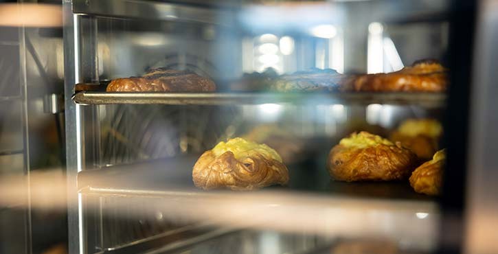 Several trays of pastries are starting to bake, turning golden brown, in a RATIONAL iCombi Pro combi-steam oven
