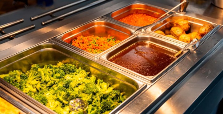 Hot school dinner buffet featuring broccoli, peas, carrots, gravy, baked beans and more, hot and ready to serve