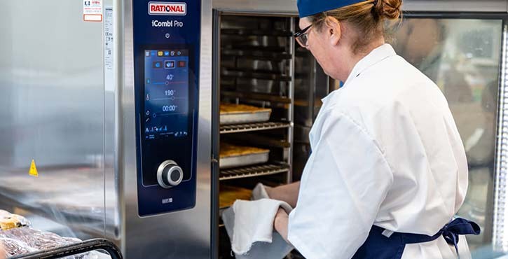 A female school cook takes 3 pies out of the iCombi Pro, perfectly cooked and golden brown.